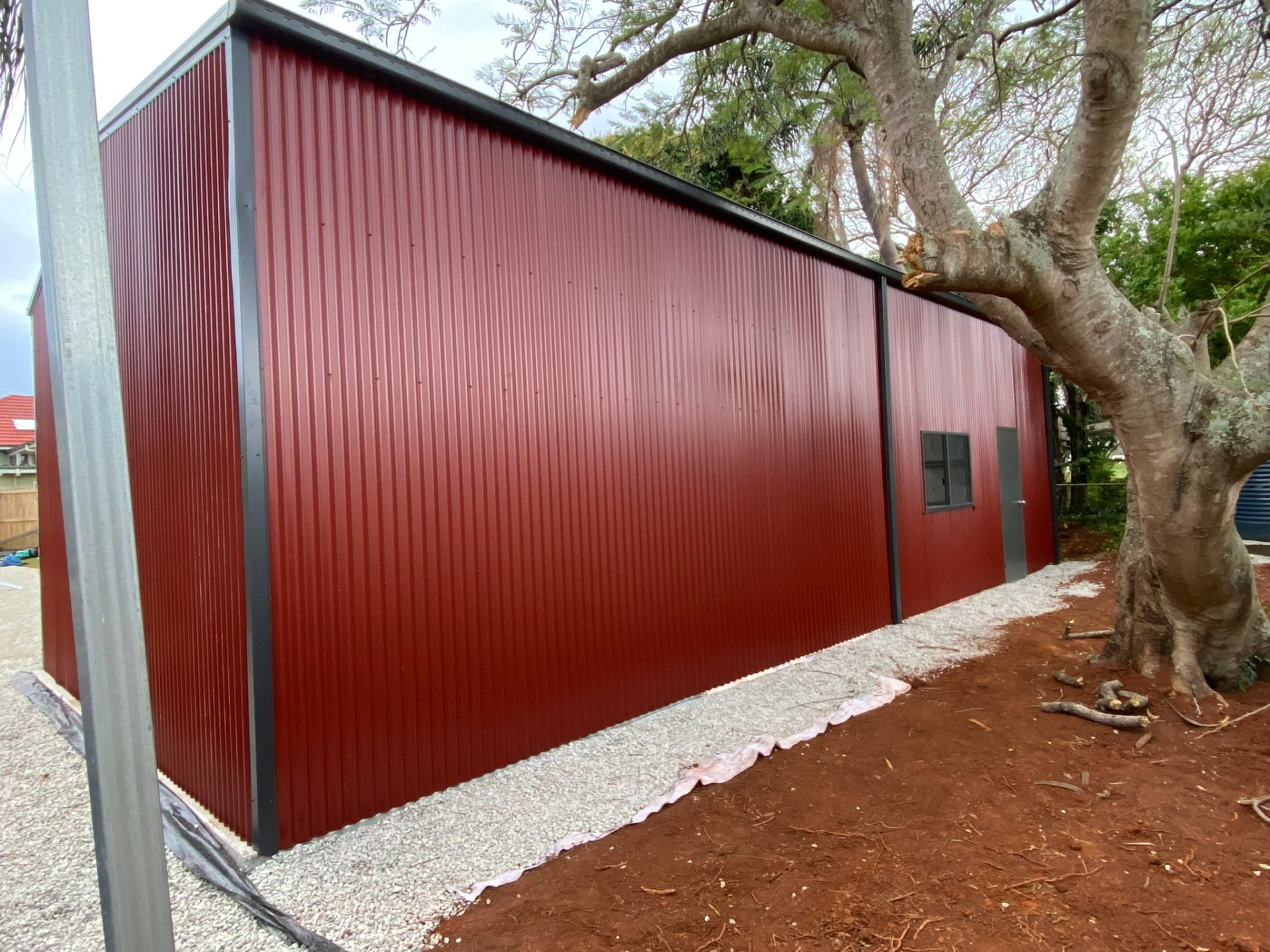 Side view of a residential steel shed set on a backyard block