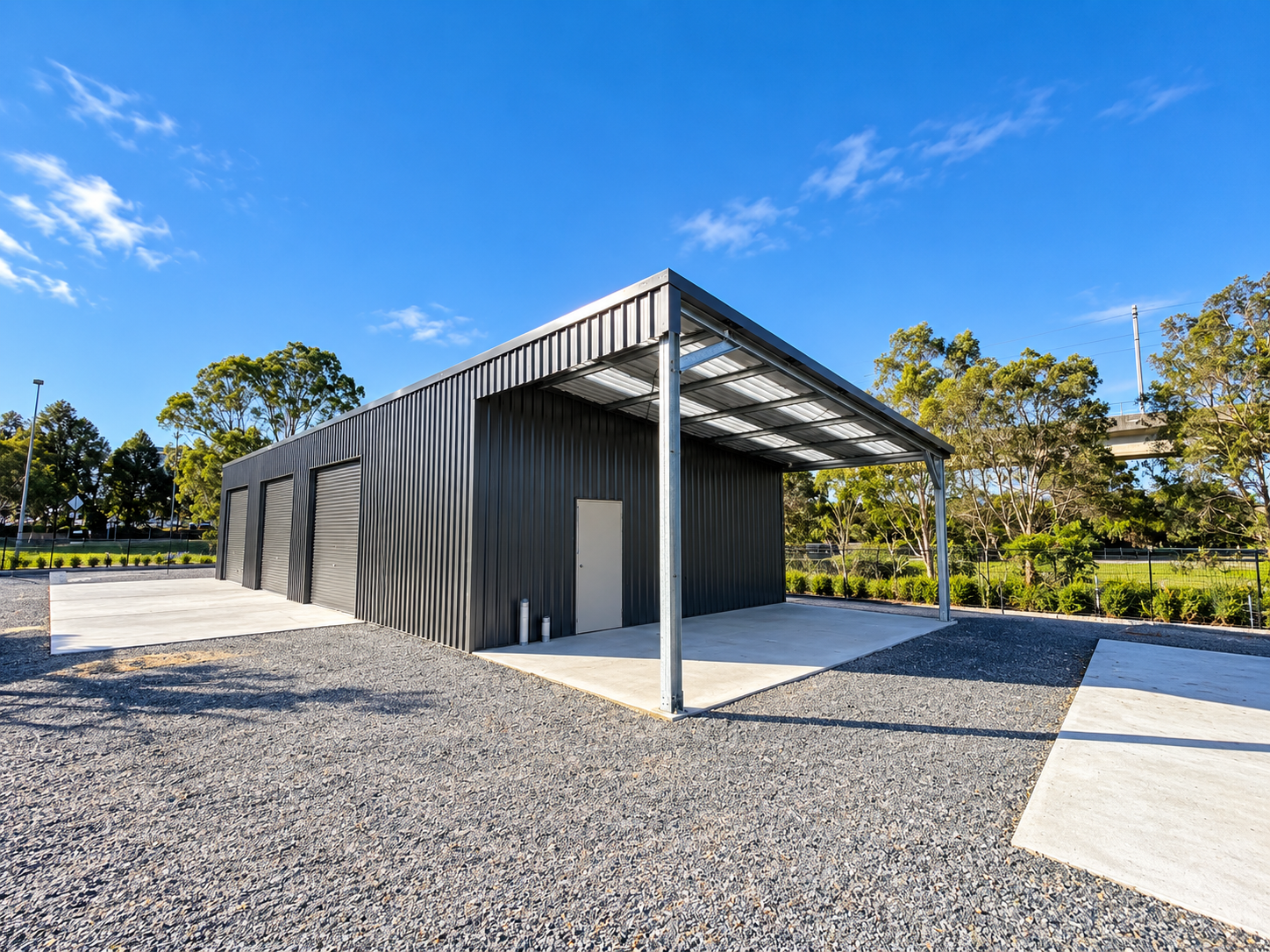 Side view of a large industrial shed with steel cladding and roller doors