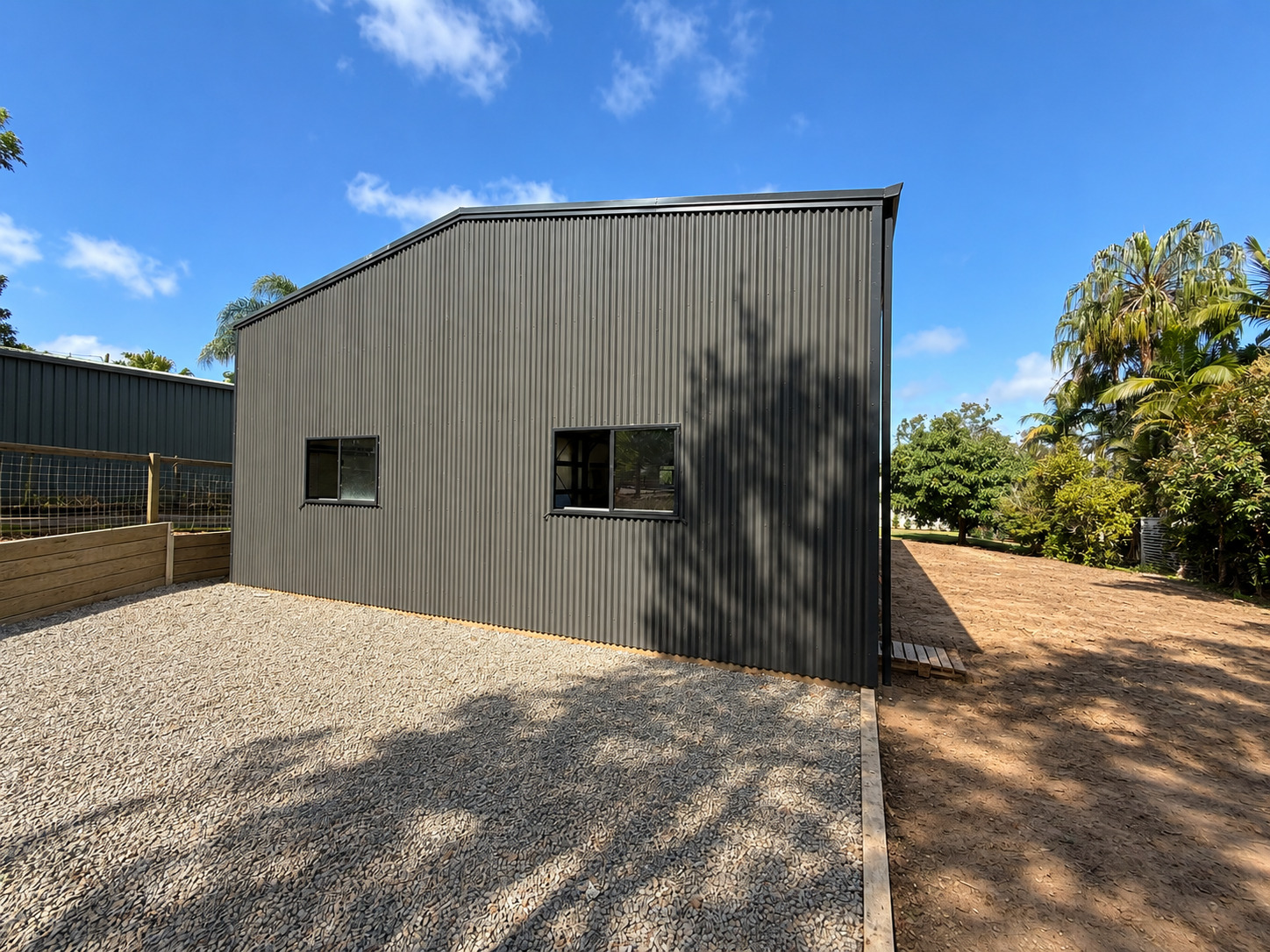 Side view of a Colorbond shed with windows and gravel driveway, Beaudesert