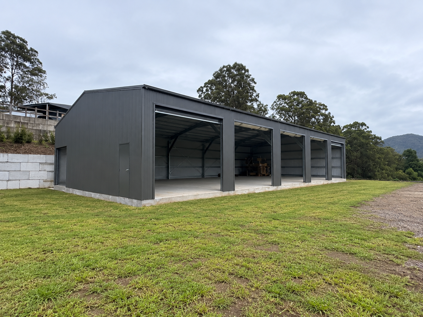 Side view of a large steel shed on an acreage property with open surrounding land