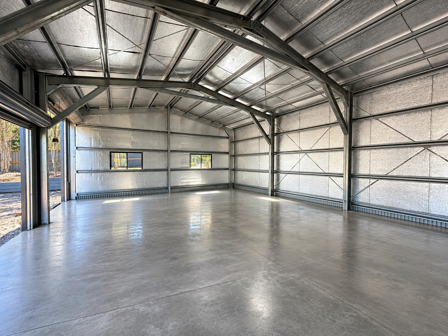 Open interior of a steel workshop shed with clear floor space for a bench and equipment