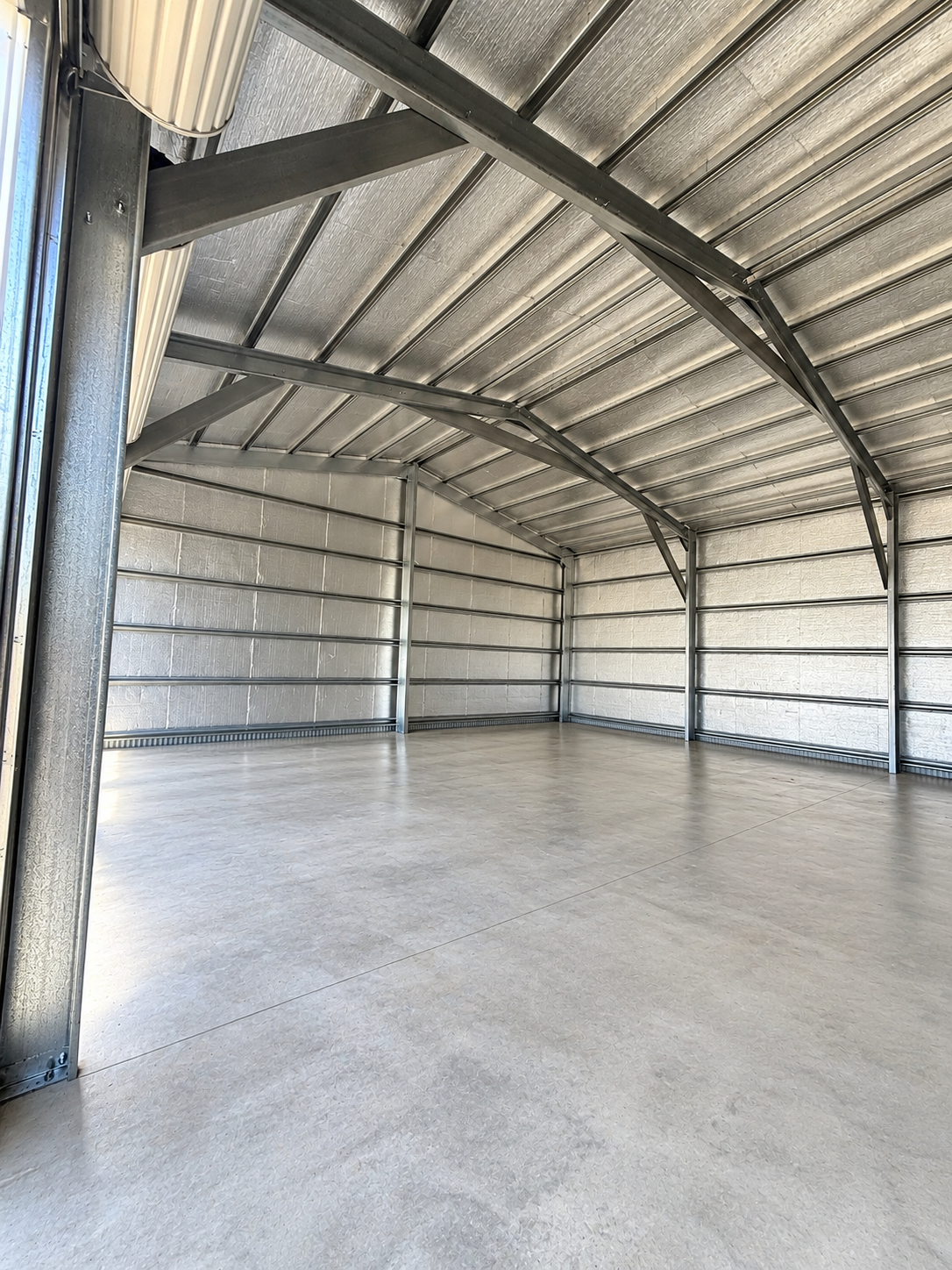 Interior of a steel shed with a clean, open workspace and natural light